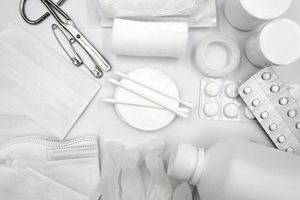 A flat lay of essential first aid supplies including bandages, gloves, and medications.